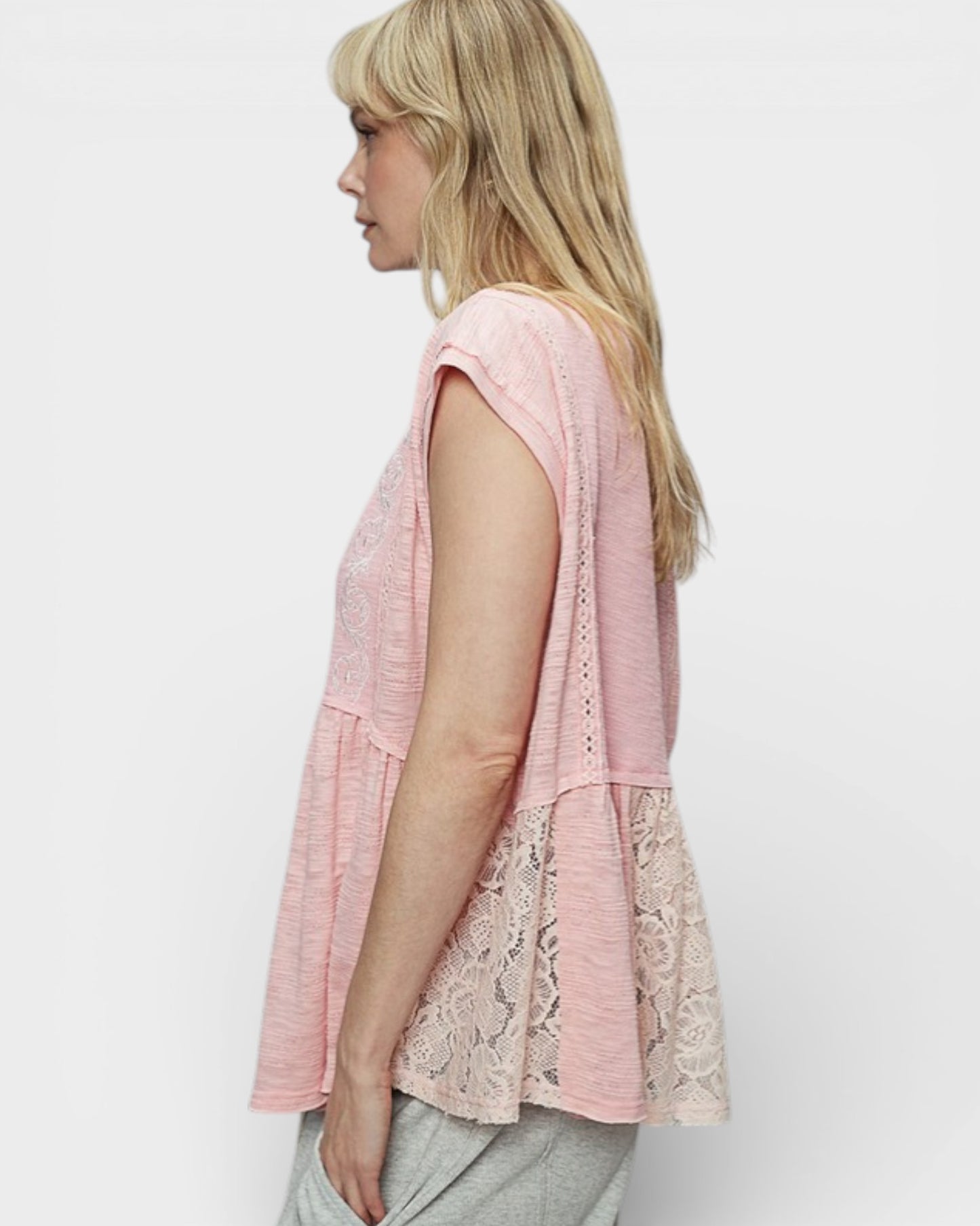 Woman wearing a pink lace top on a white background