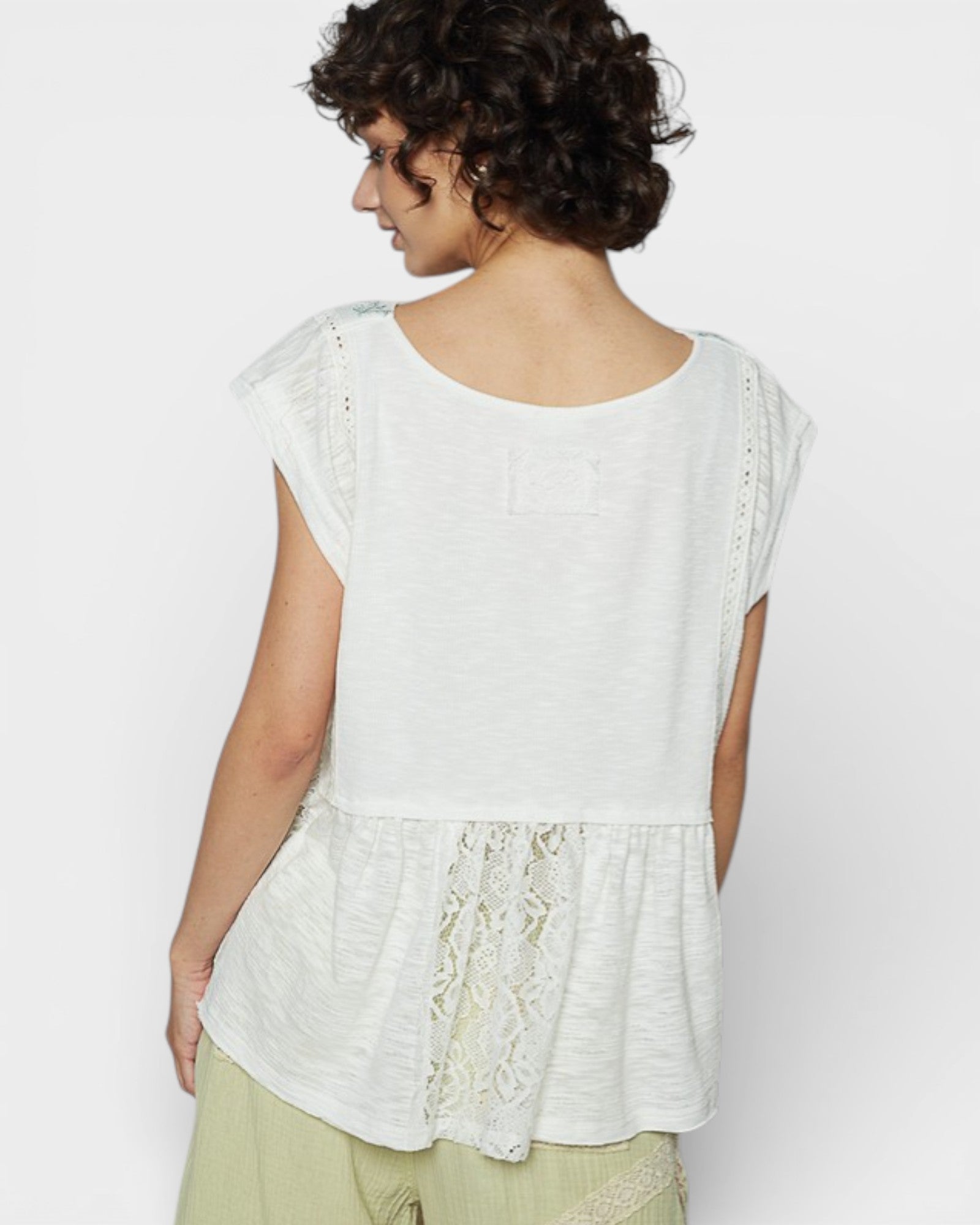 Woman wearing a white lace top with a plain background