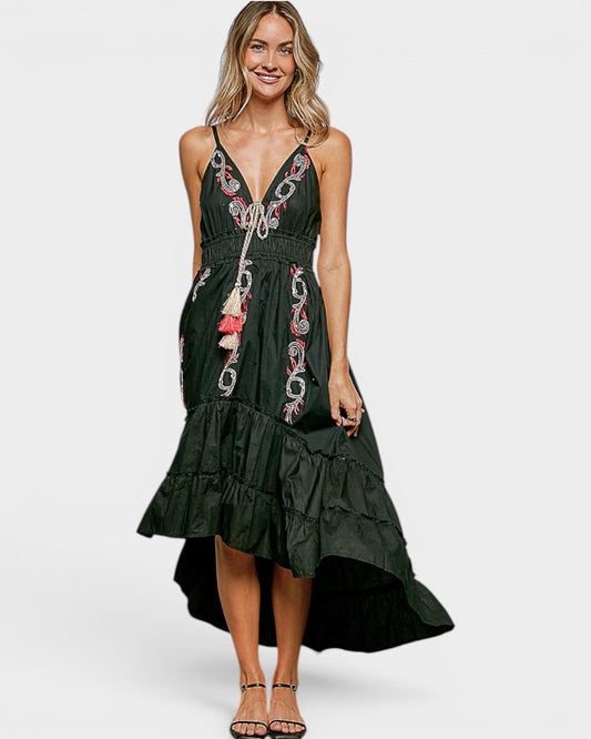 Woman wearing a black dress with floral embroidery on a white background