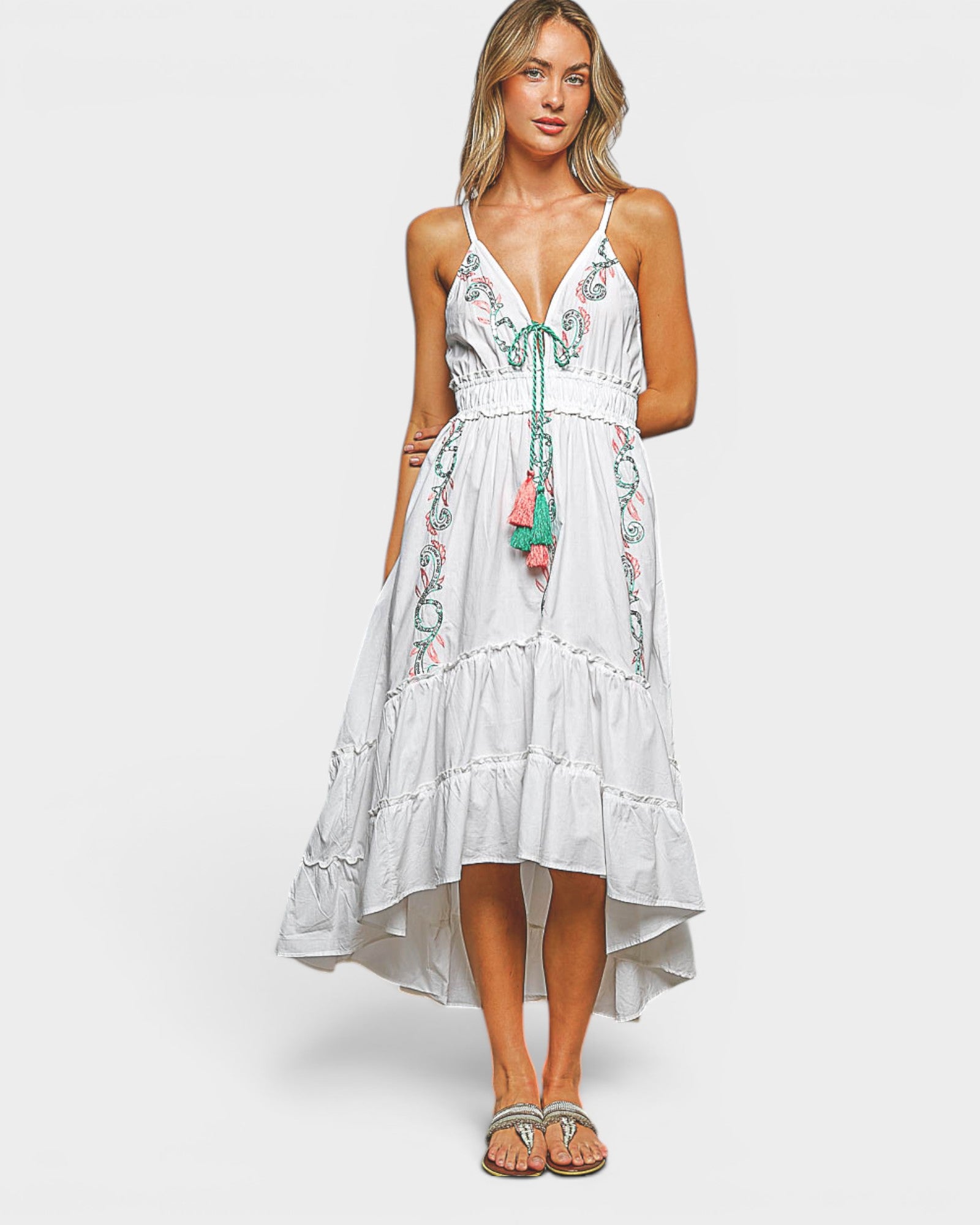Woman wearing a white dress with floral embroidery on a plain background