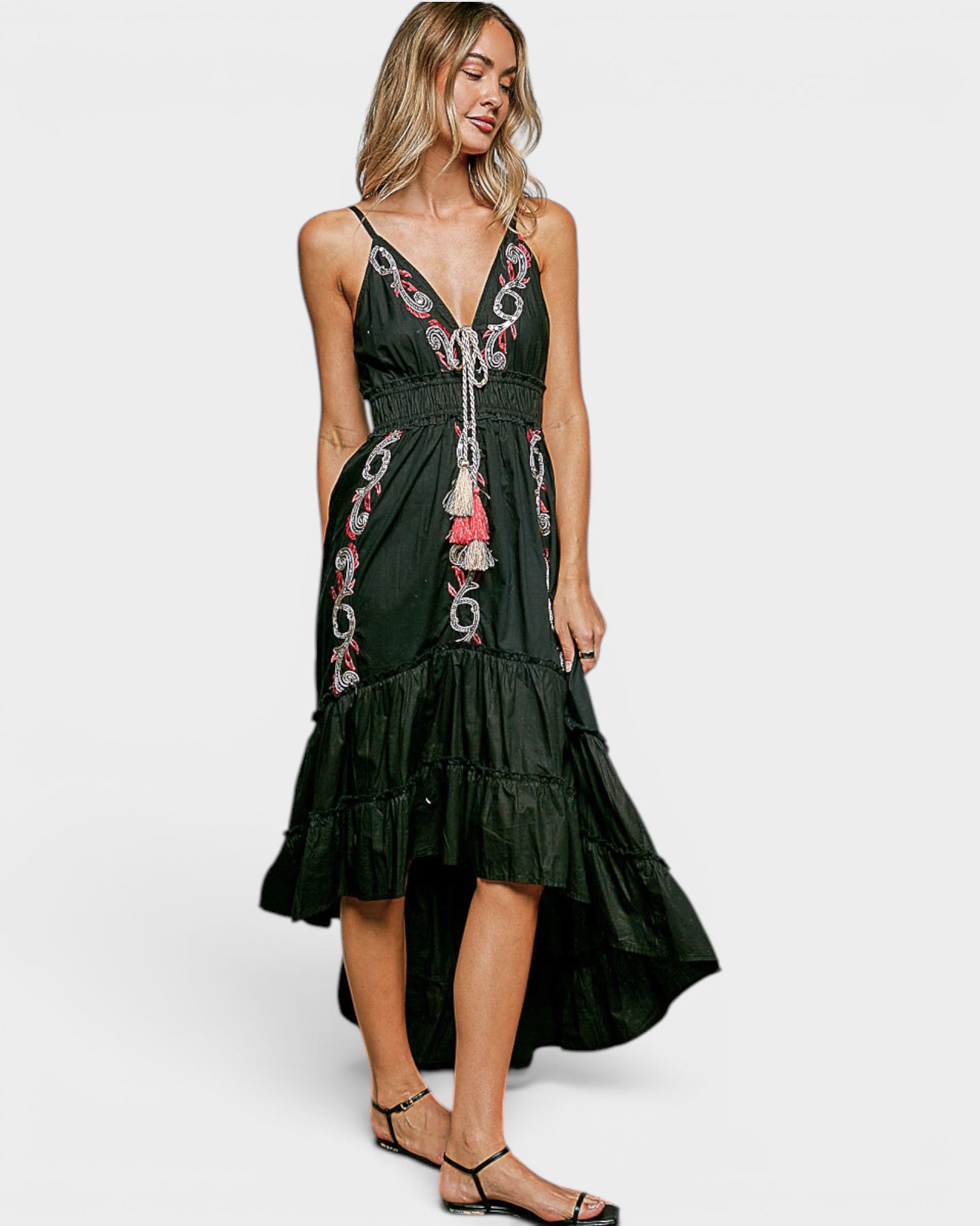 Woman wearing a black dress with floral embroidery on a white background