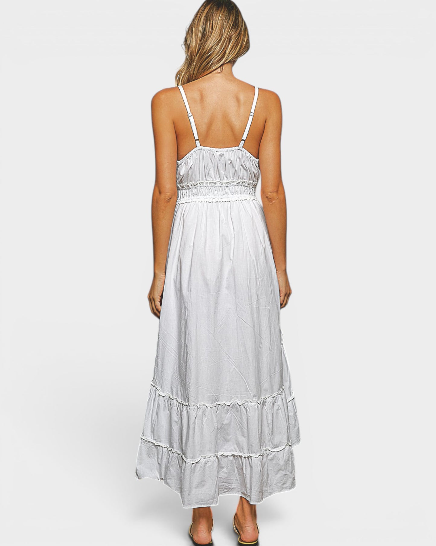 Woman wearing a white dress with thin straps on a plain background