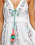 White dress with intricate embroidery and colorful tassel details on a plain background