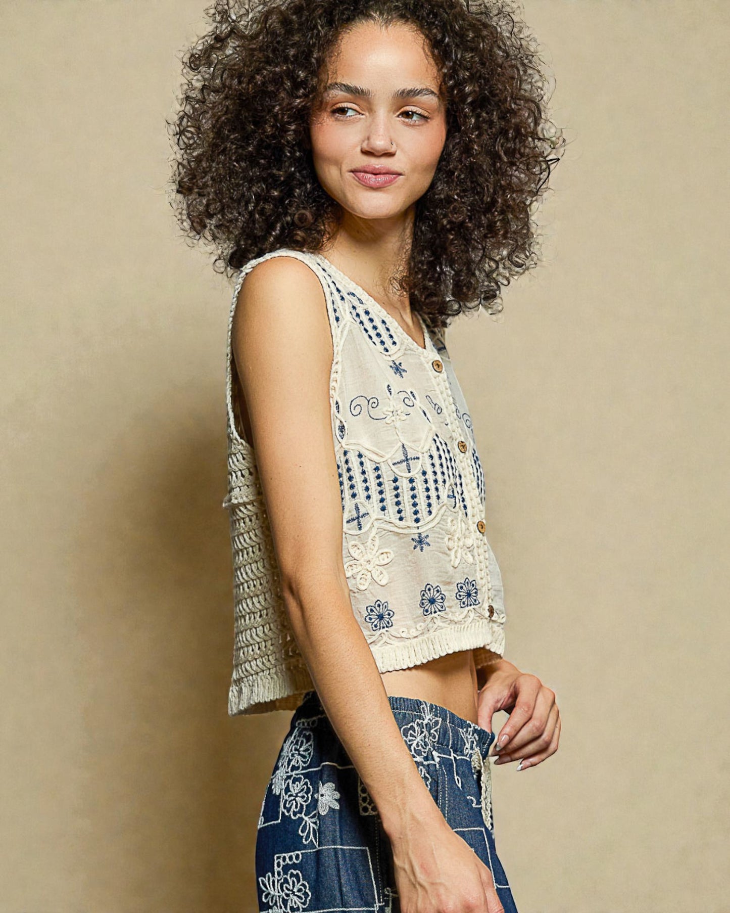 Woman wearing a sleeveless top with floral patterns against a beige background