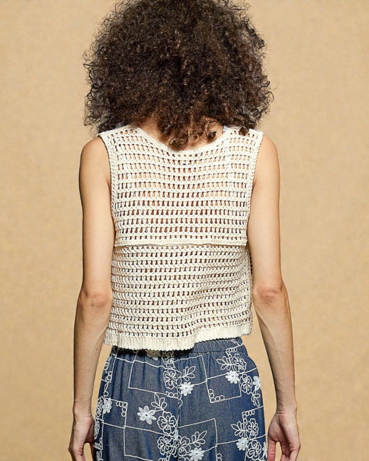 Person wearing a sleeveless crochet top with a beige background