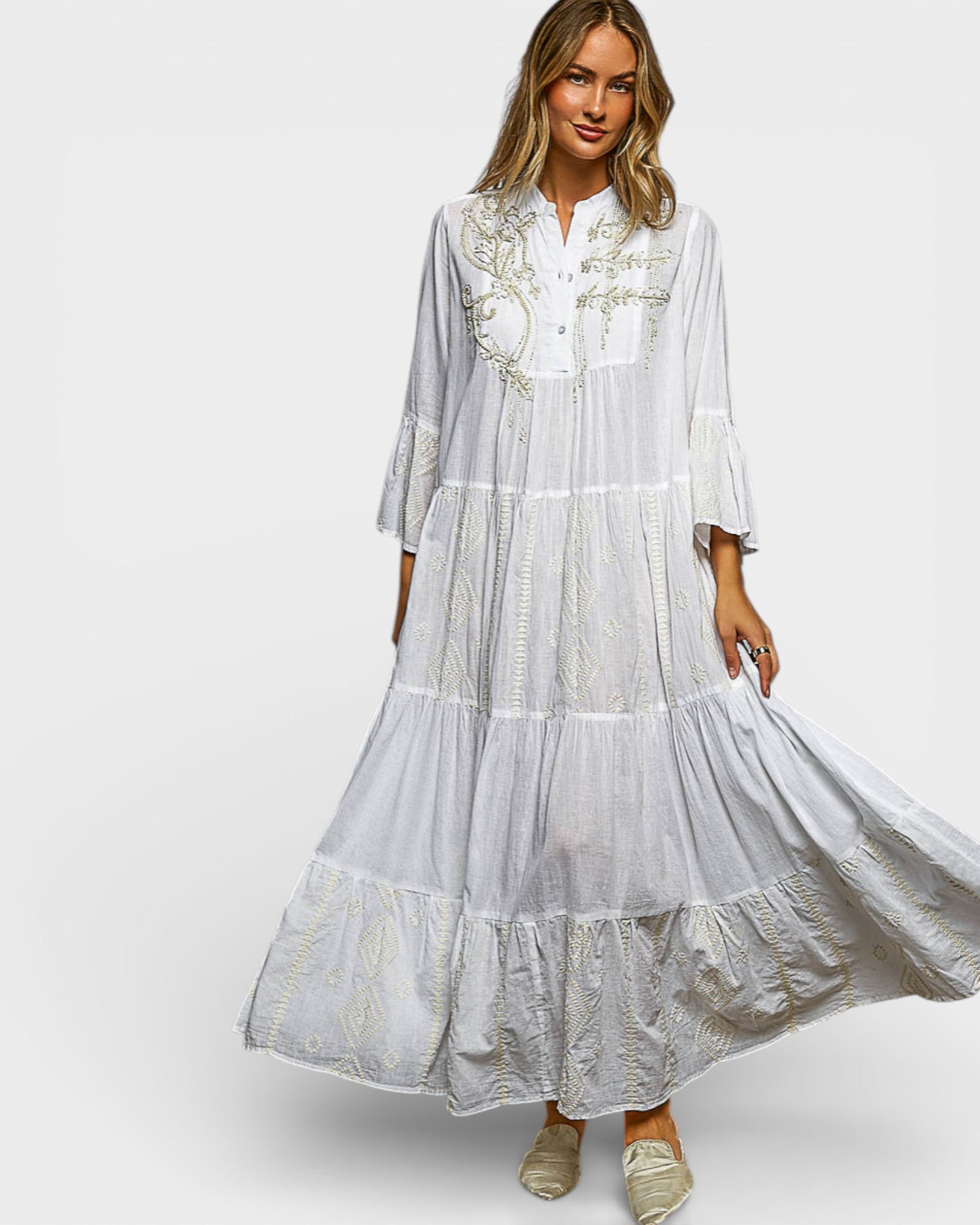 Woman wearing a white embroidered dress on a plain background