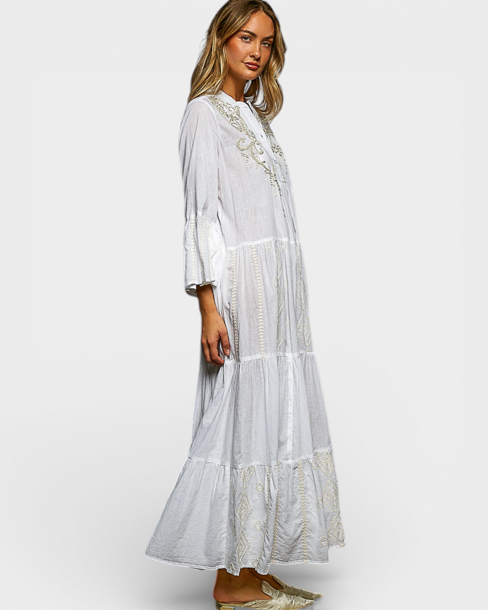 Woman wearing a white embroidered dress on a white background