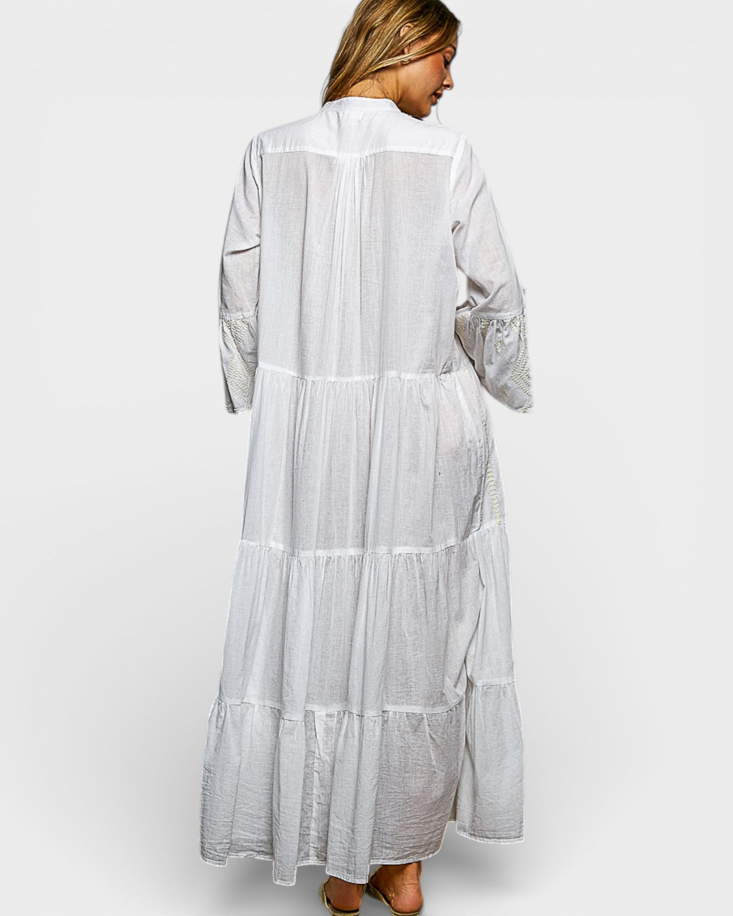 Woman wearing a long, light gray dress with lace details on a white background