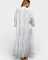Woman wearing a long, light gray dress with lace details on a white background