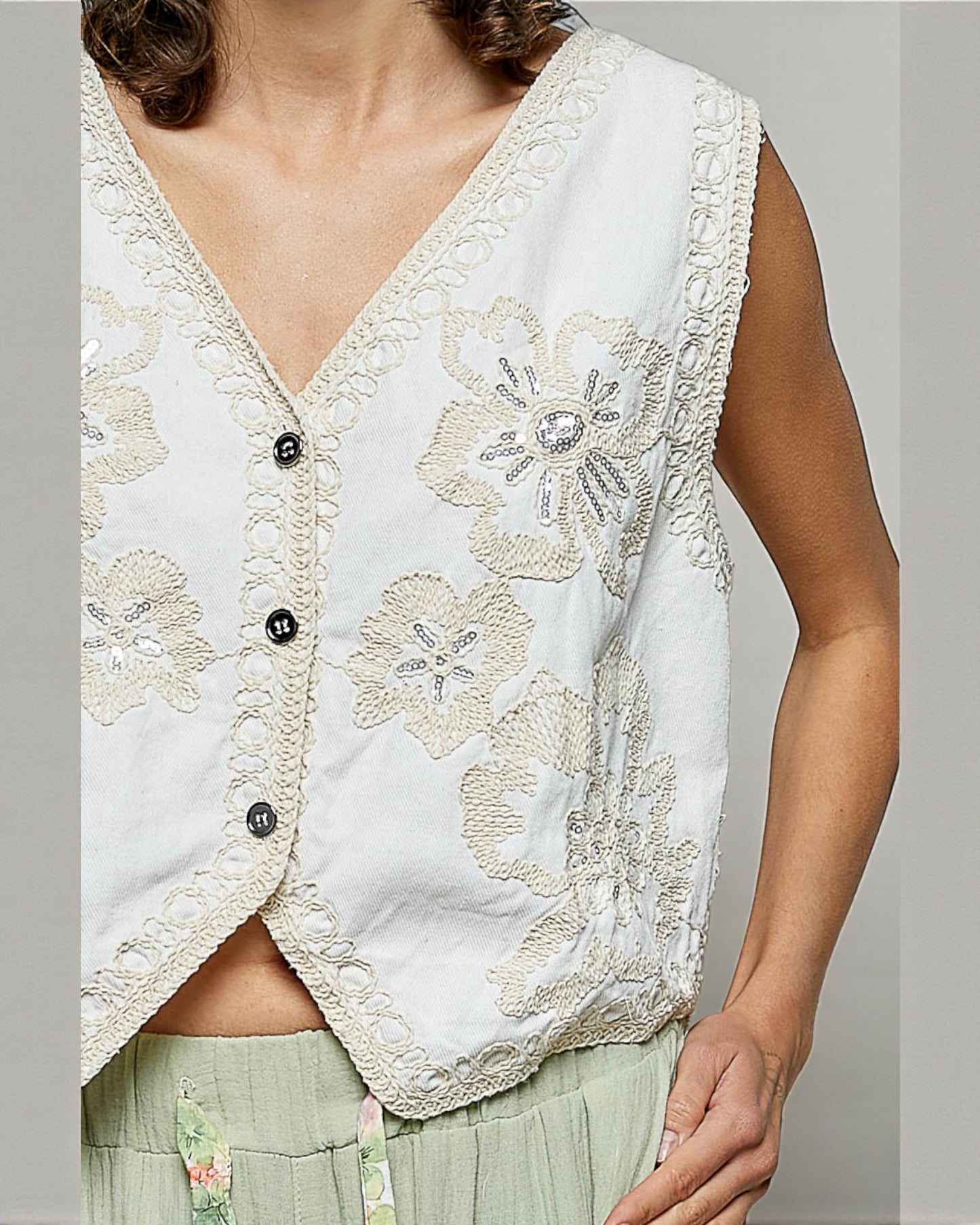 White embroidered vest worn by a person on a plain background