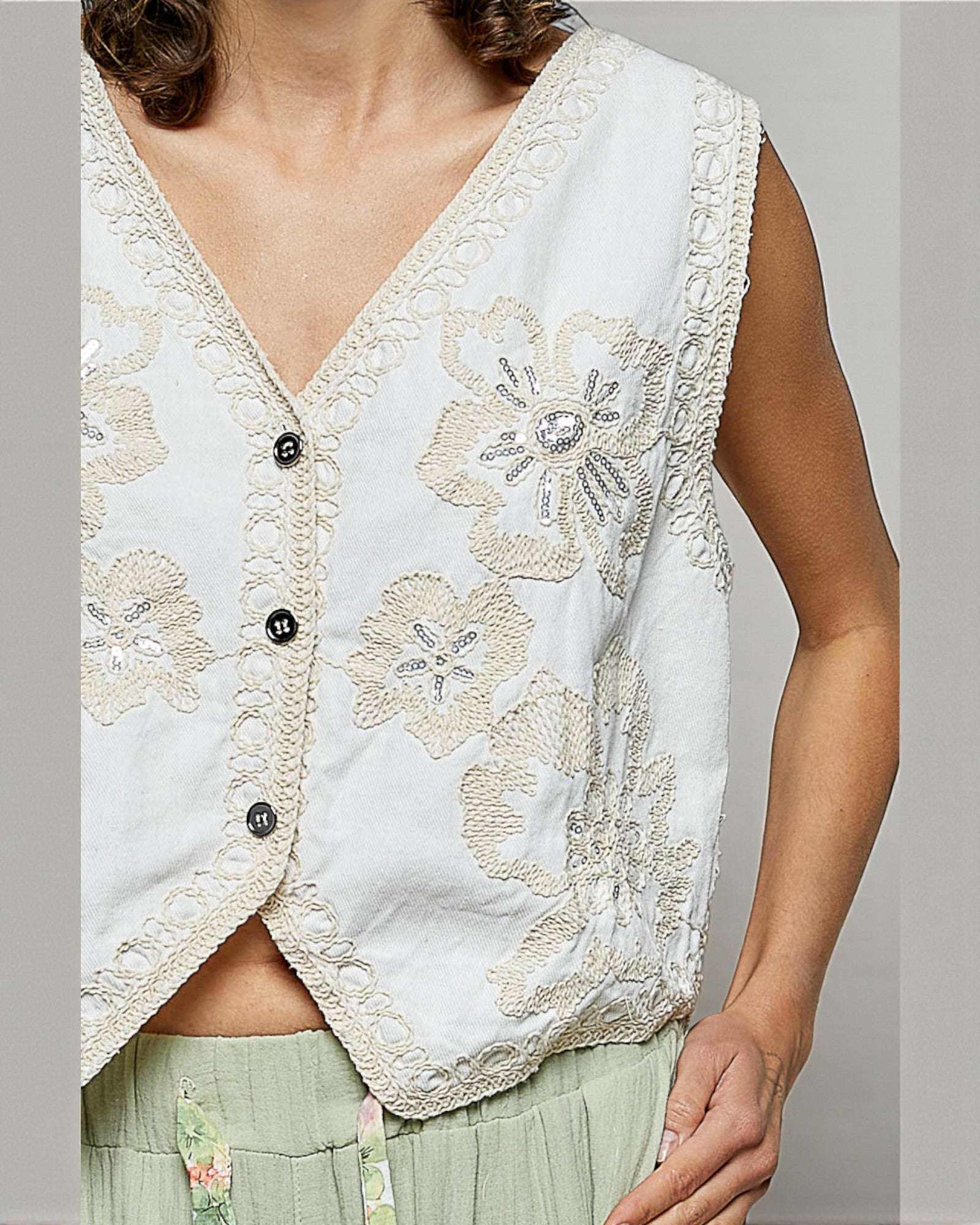White embroidered vest worn by a person on a plain background