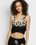 Woman wearing a black crop top with butterfly embellishments on a white background