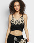 Woman wearing a black top with butterfly designs on a plain background