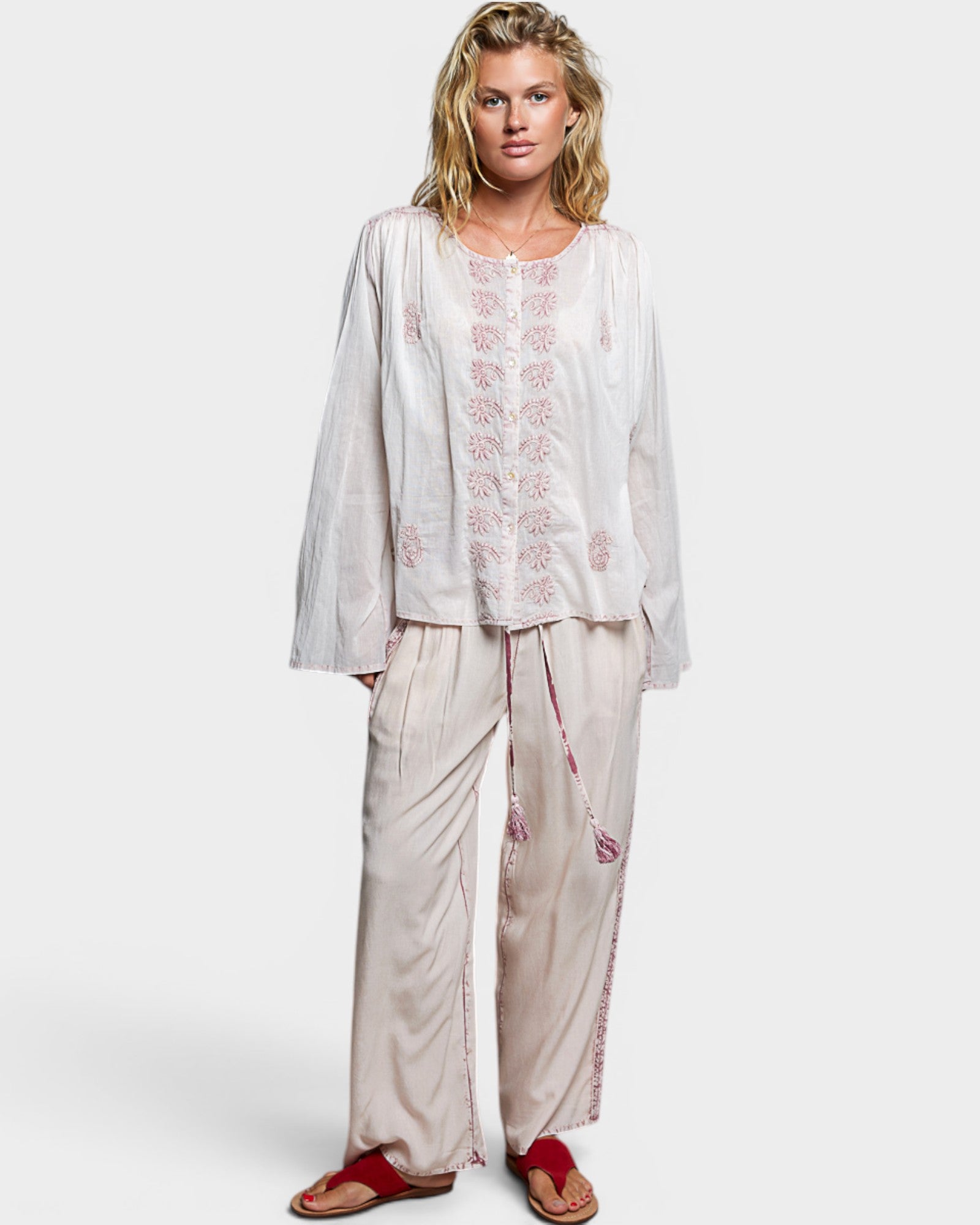 Woman wearing a white embroidered outfit on a plain background