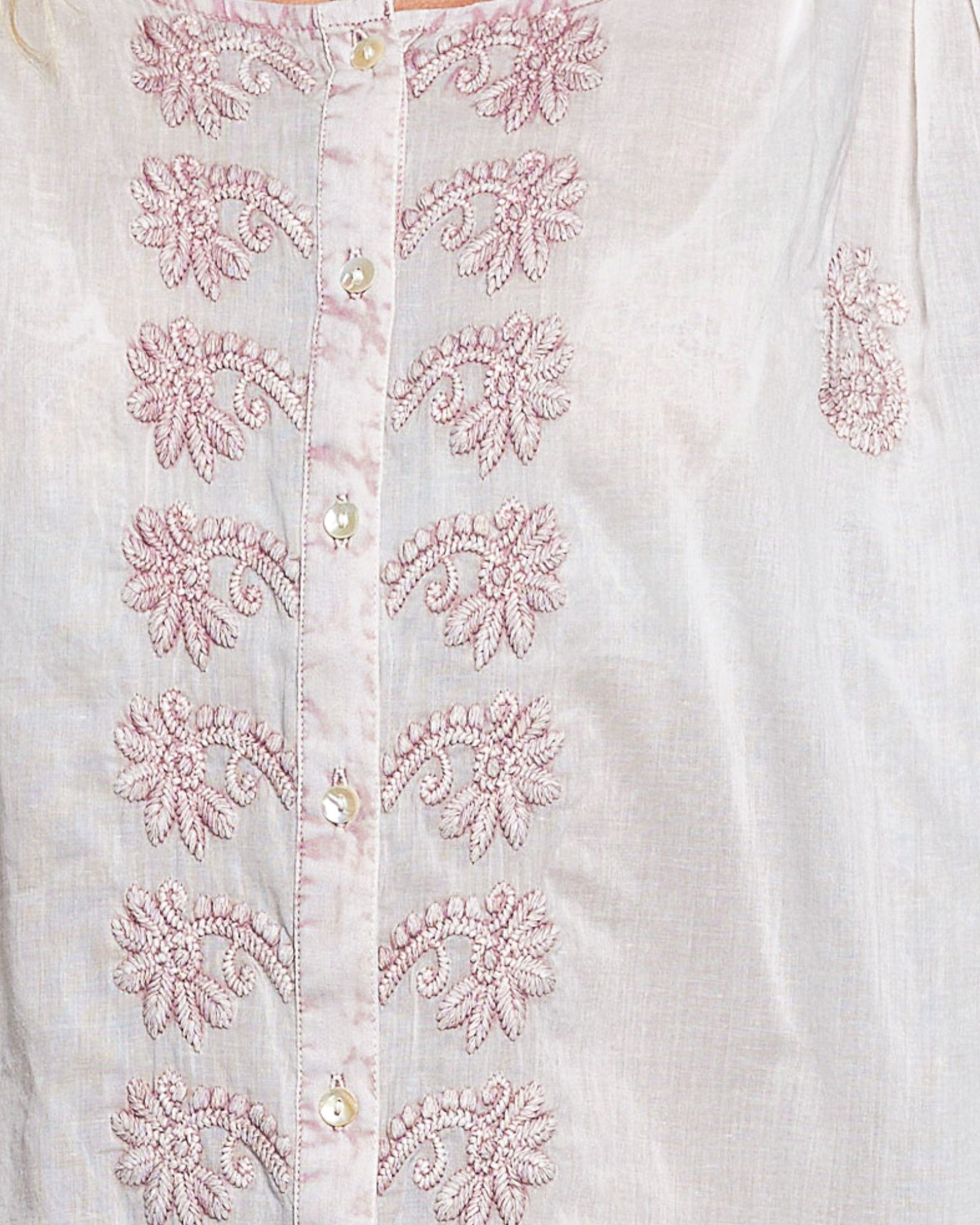 White shirt with pink floral embroidery on a light background