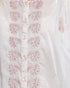 White shirt with pink floral embroidery on a light background