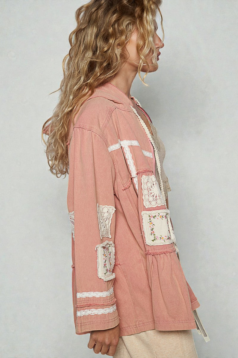 Woman wearing a pink jacket with lace details on a plain background