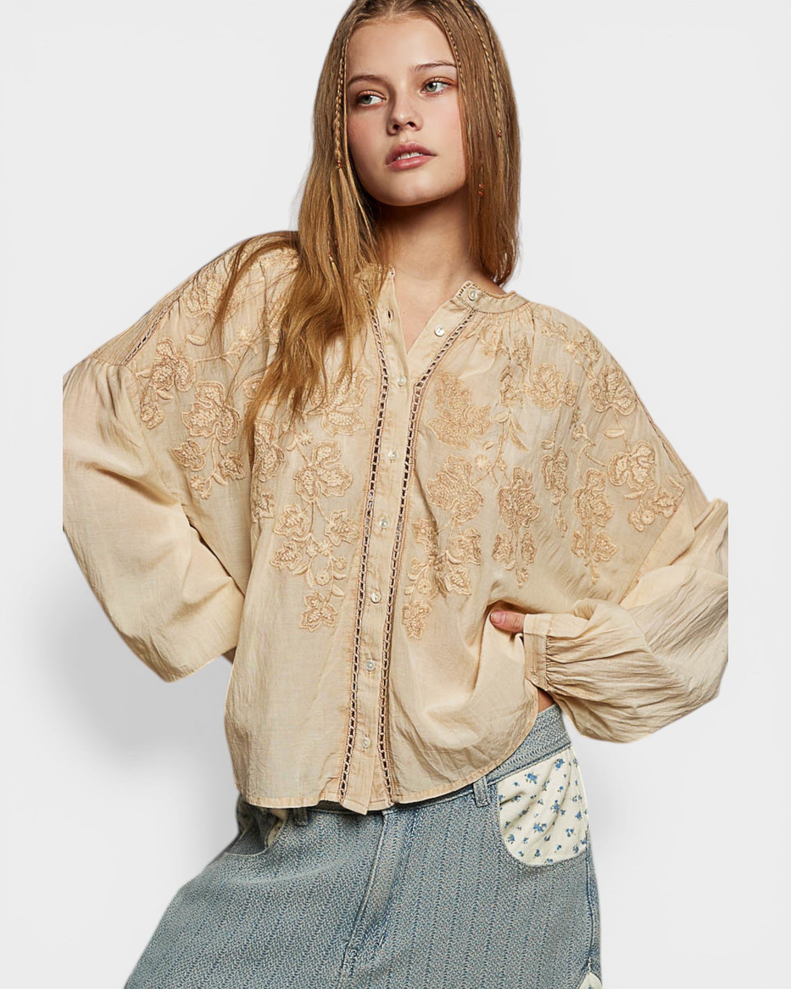 Woman wearing a beige embroidered blouse with a white background