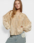 Woman wearing a beige embroidered blouse with a white background