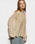 Woman wearing a beige embroidered blouse against a white background
