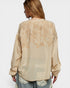 Woman wearing a beige embroidered blouse on a white background