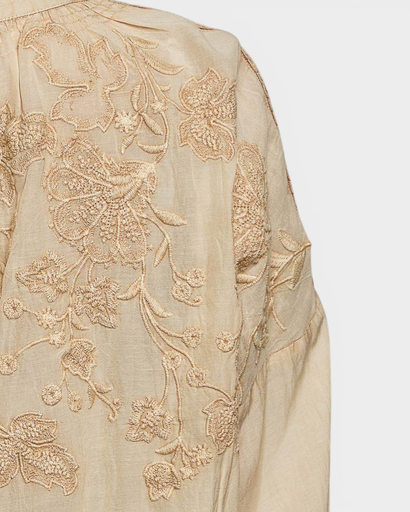 Beige fabric with intricate gold embroidery on a white background