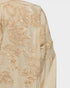 Beige fabric with intricate gold embroidery on a white background