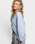 Woman wearing a light blue sweatshirt over a striped outfit on a white background