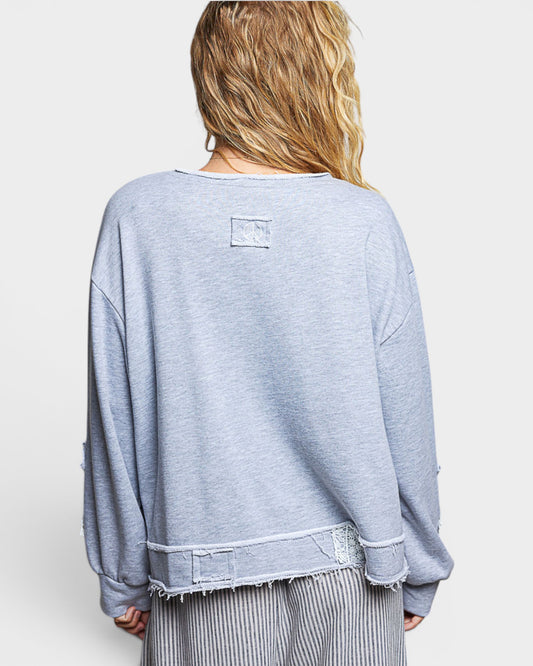 Person wearing a light blue sweatshirt with a visible brand logo on a white background
