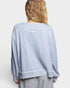 Person wearing a light blue sweatshirt with a visible brand logo on a white background