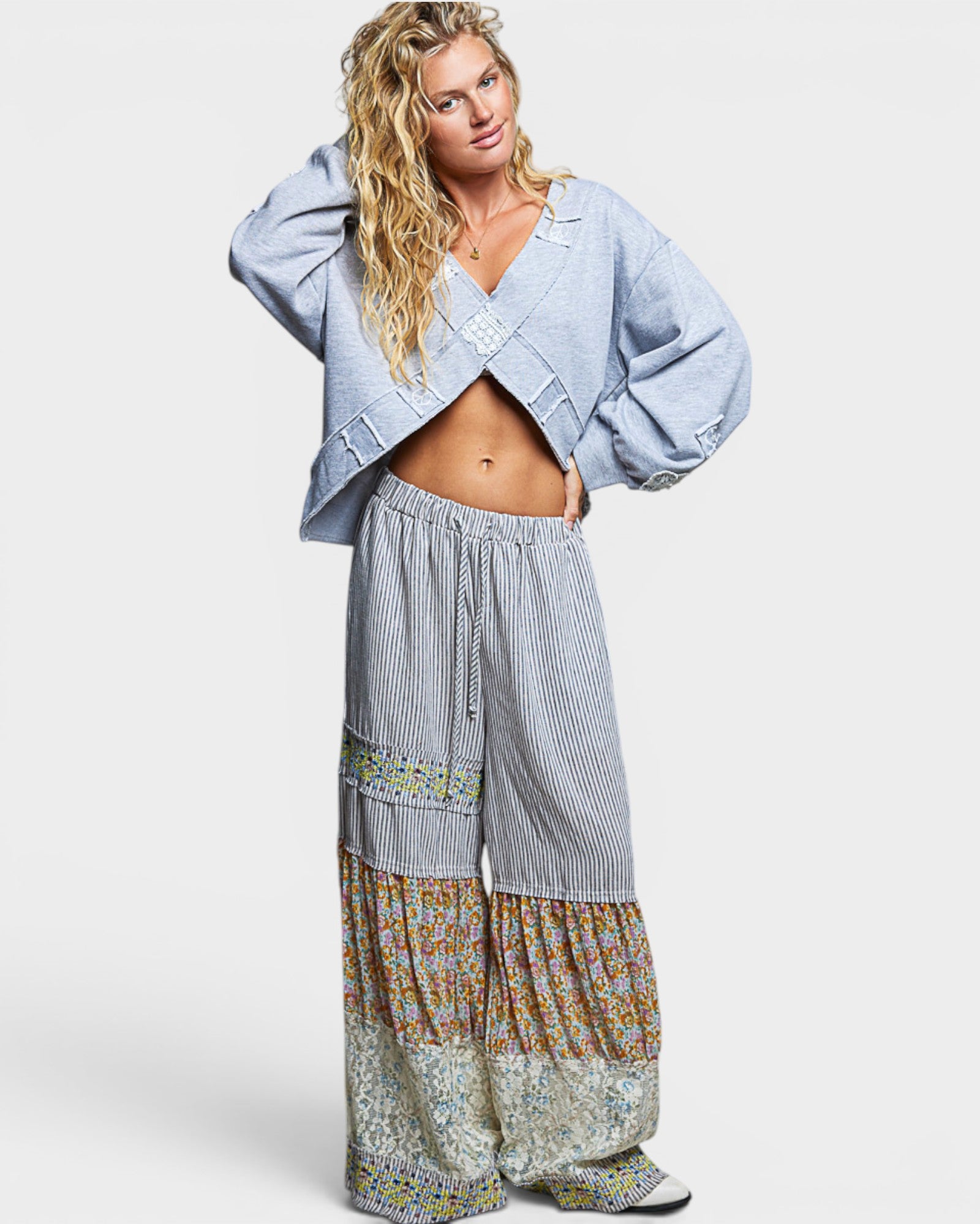 Woman wearing a light blue sweatshirt and patterned pants on a white background