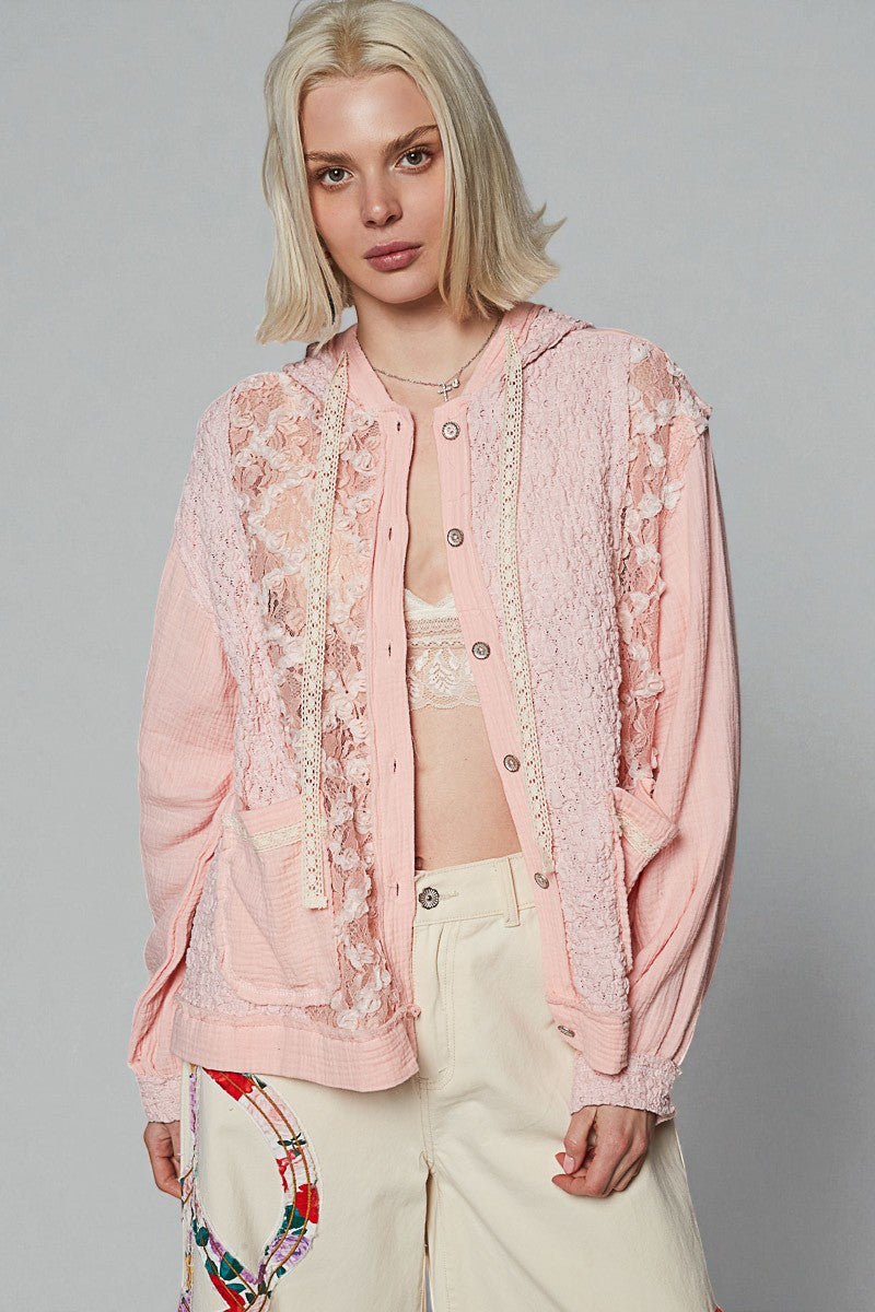 Woman wearing a pink floral lace top with a plain background