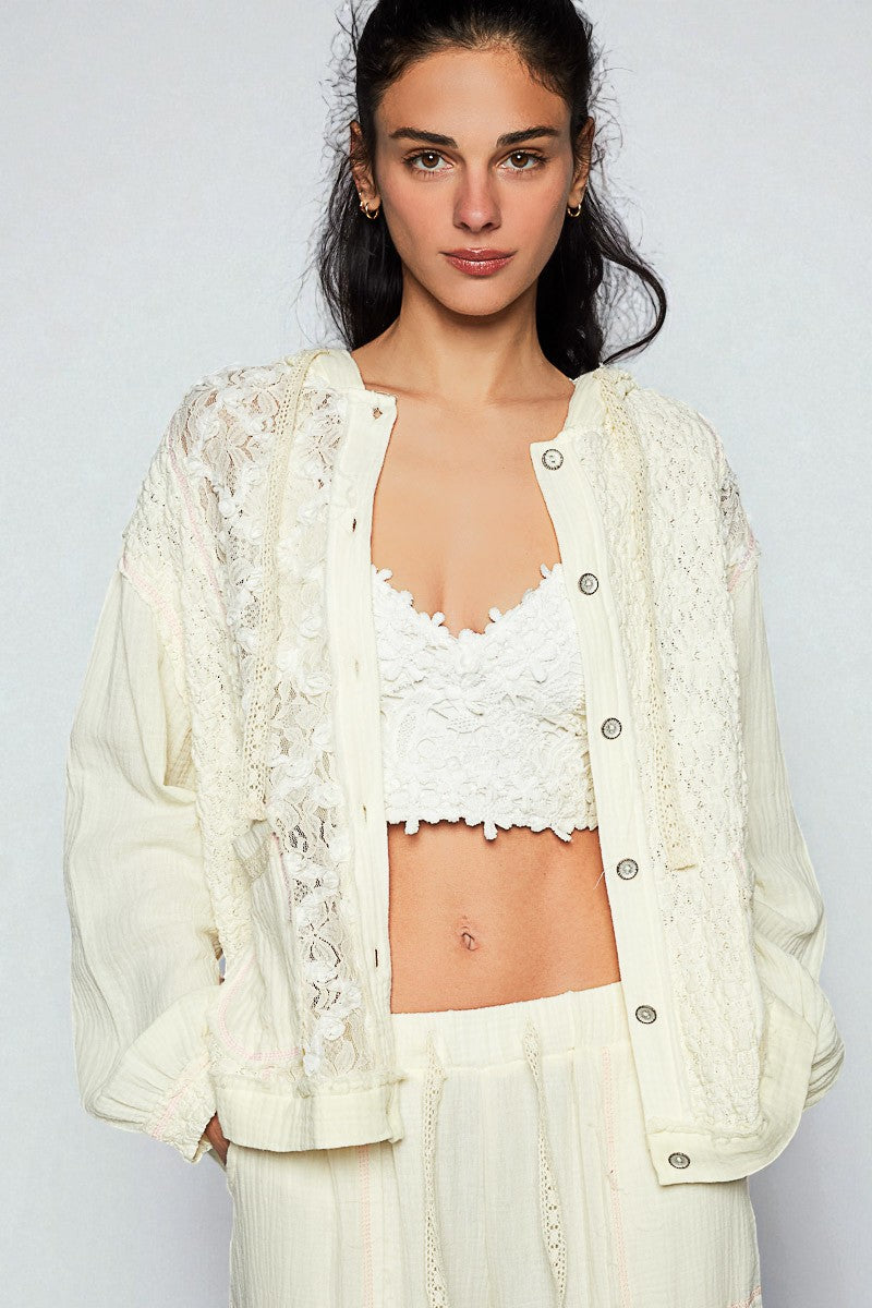Woman wearing a white lace cardigan over a matching top and pants against a plain background