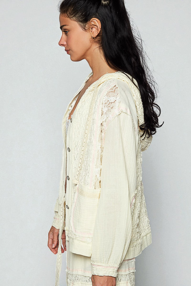 Woman wearing a light-colored lace outfit against a plain background