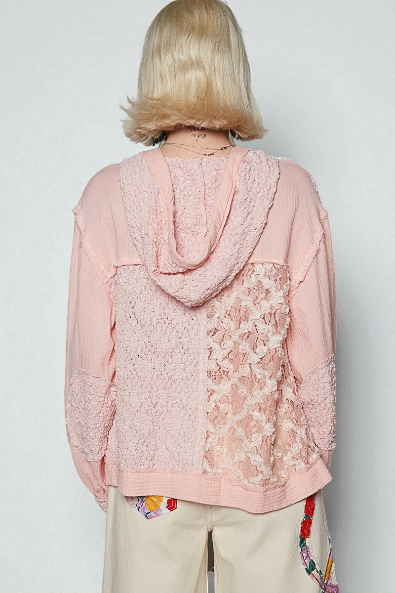 Person wearing a pink lace-trimmed top with a plain background