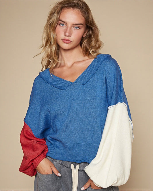 Woman wearing a blue sweater with red and white sleeves on a beige background