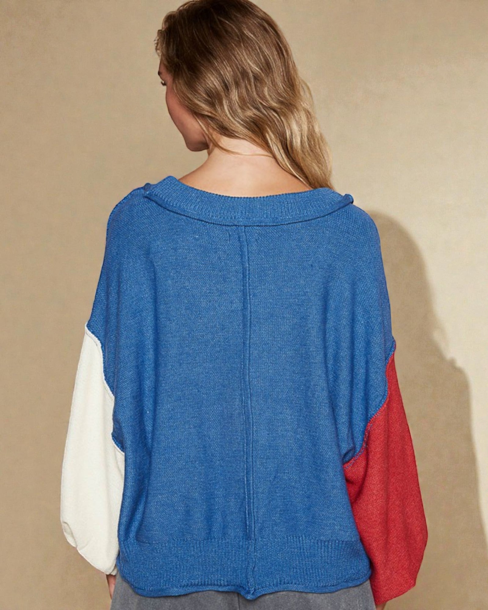 Person wearing a blue, white, and red color-blocked sweater against a beige background