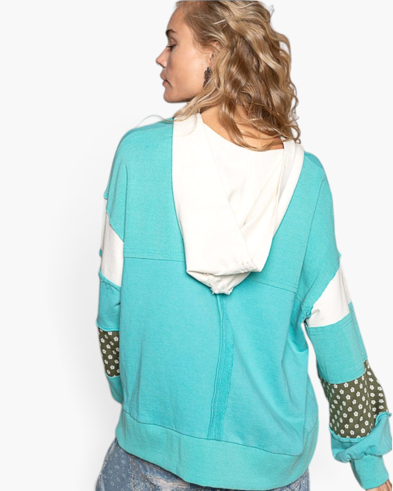 A woman shown from the back wearing a turquoise and white color-block hoodie with patterned elbow patches, against a plain white background.