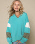 Woman wearing a teal sweater with polka dot cuffs and hem on a beige background