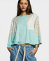 Woman wearing a light blue top with floral sleeves and blue pants on a white background