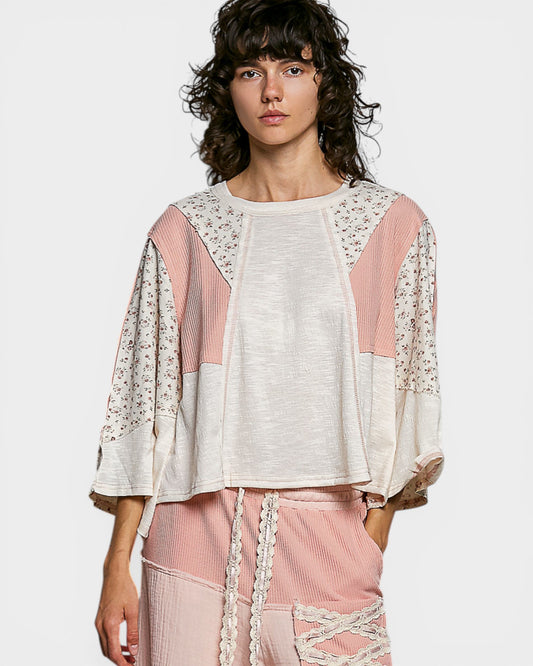 Woman wearing a white and pink outfit with floral patterns on a plain background