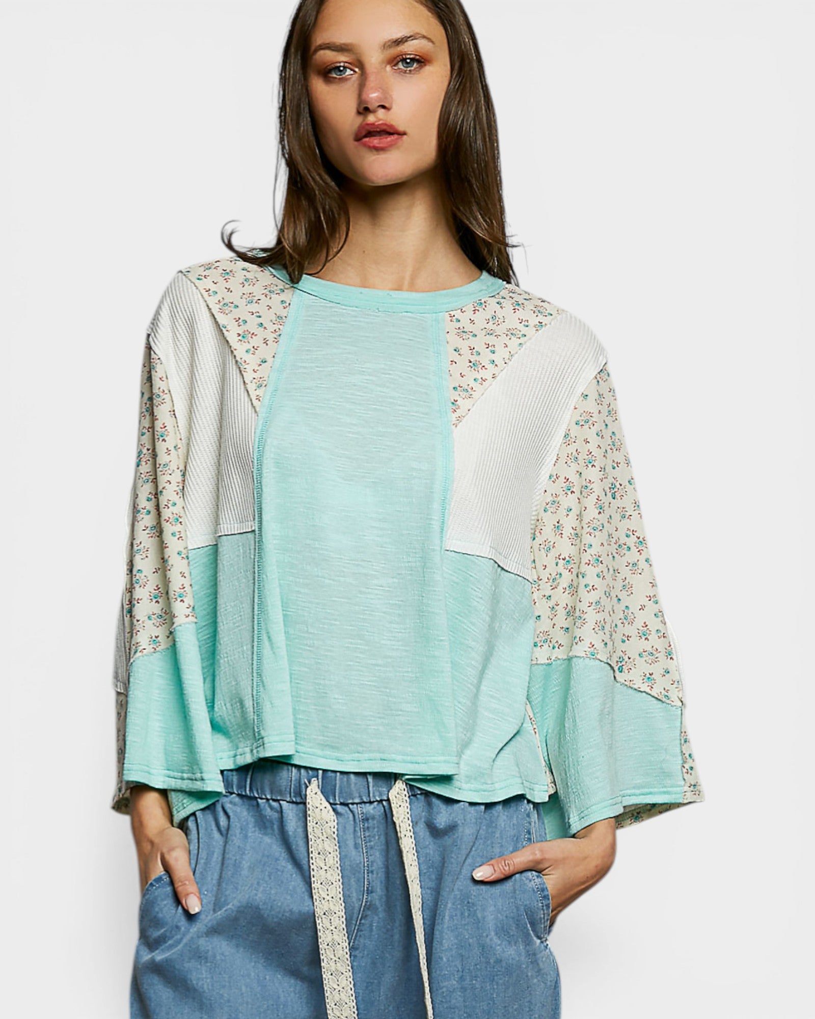 Woman wearing a light blue top with floral sleeves against a white background