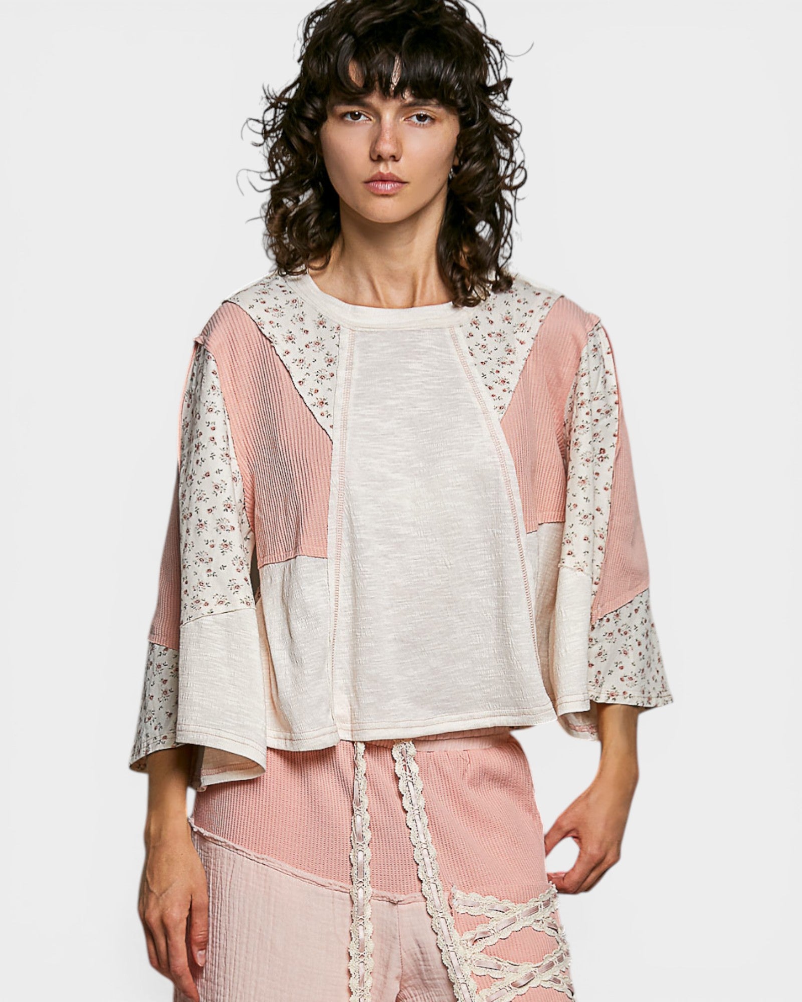 Woman wearing a white and pink outfit with lace details on a white background