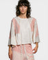 Woman wearing a white and pink outfit with lace details on a white background