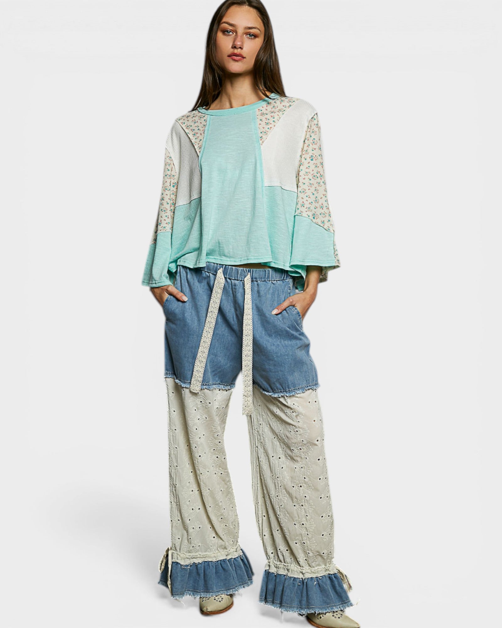 Woman wearing a patchwork outfit with a light blue top and denim pants on a white background