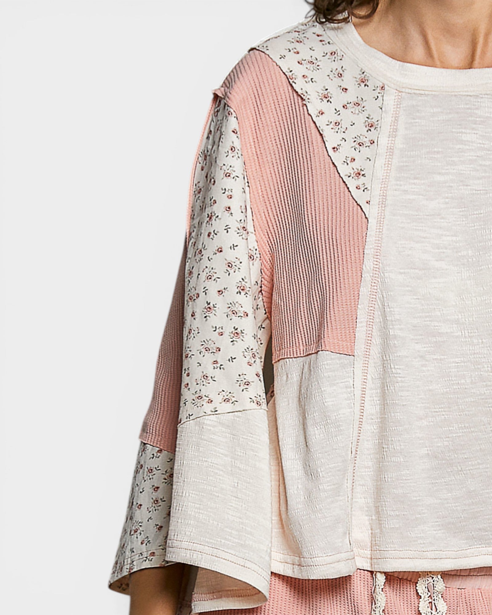 Light-colored top with floral and striped patterns on a plain background