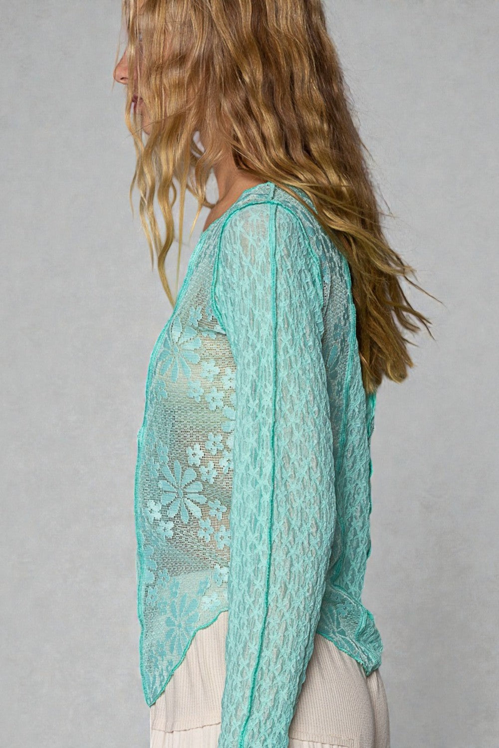 Woman wearing a light blue lace top against a gray background