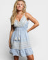 Woman wearing a light blue dress with white lace details on a plain background
