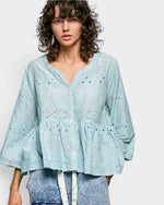 Woman wearing a light blue blouse with a white background