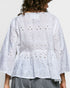 White embroidered blouse worn by a person on a plain background